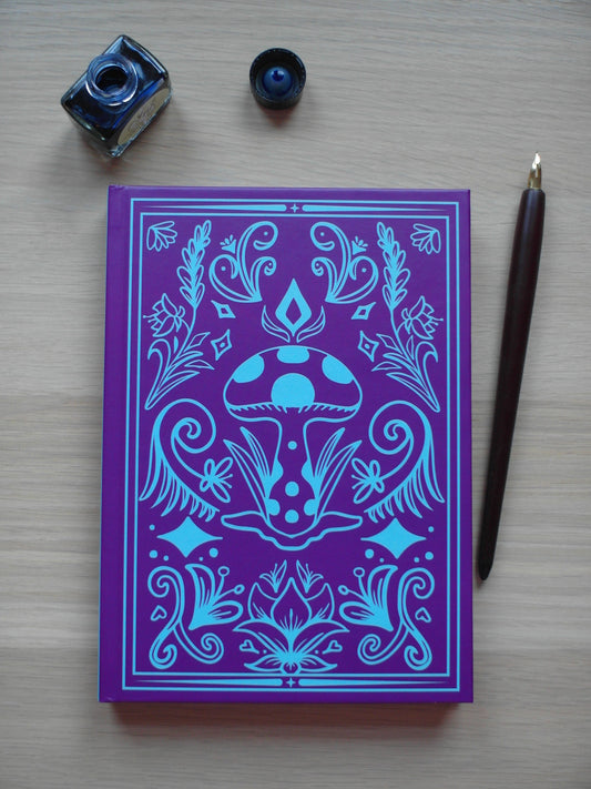 Purple and cyan hardback journal featuring designs of floral flourishes and swirls around a central mushroom - image decor of a pen and ink pot